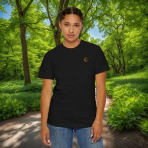 Person wearing a black T-shirt stands on a dirt forest path surrounded by dense green trees and plants.