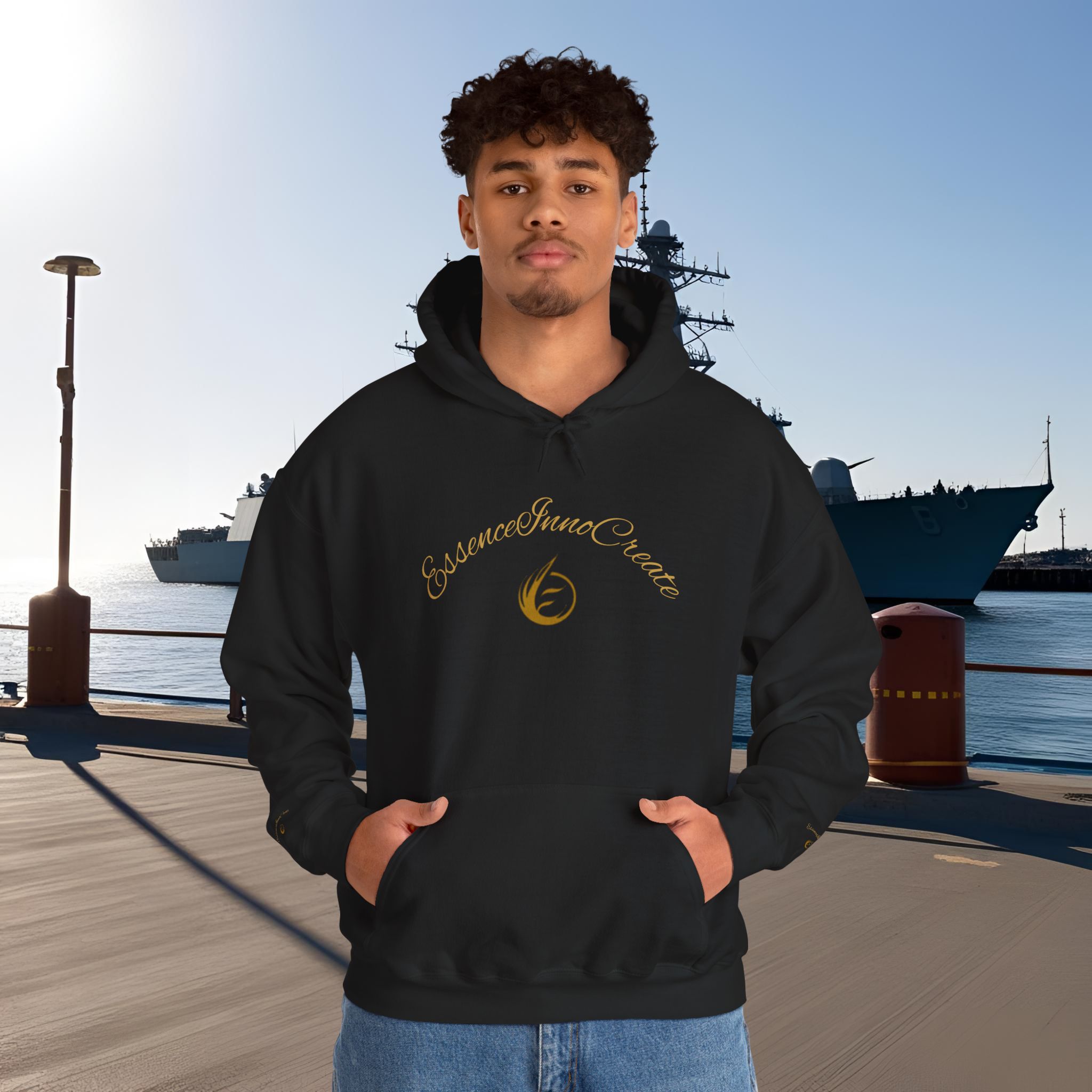 12218416965796551891_2048_customjpeg - Essence Innovation Young man in a black hoodie stands at a harbor with a large ship behind him and bright sun to the left.