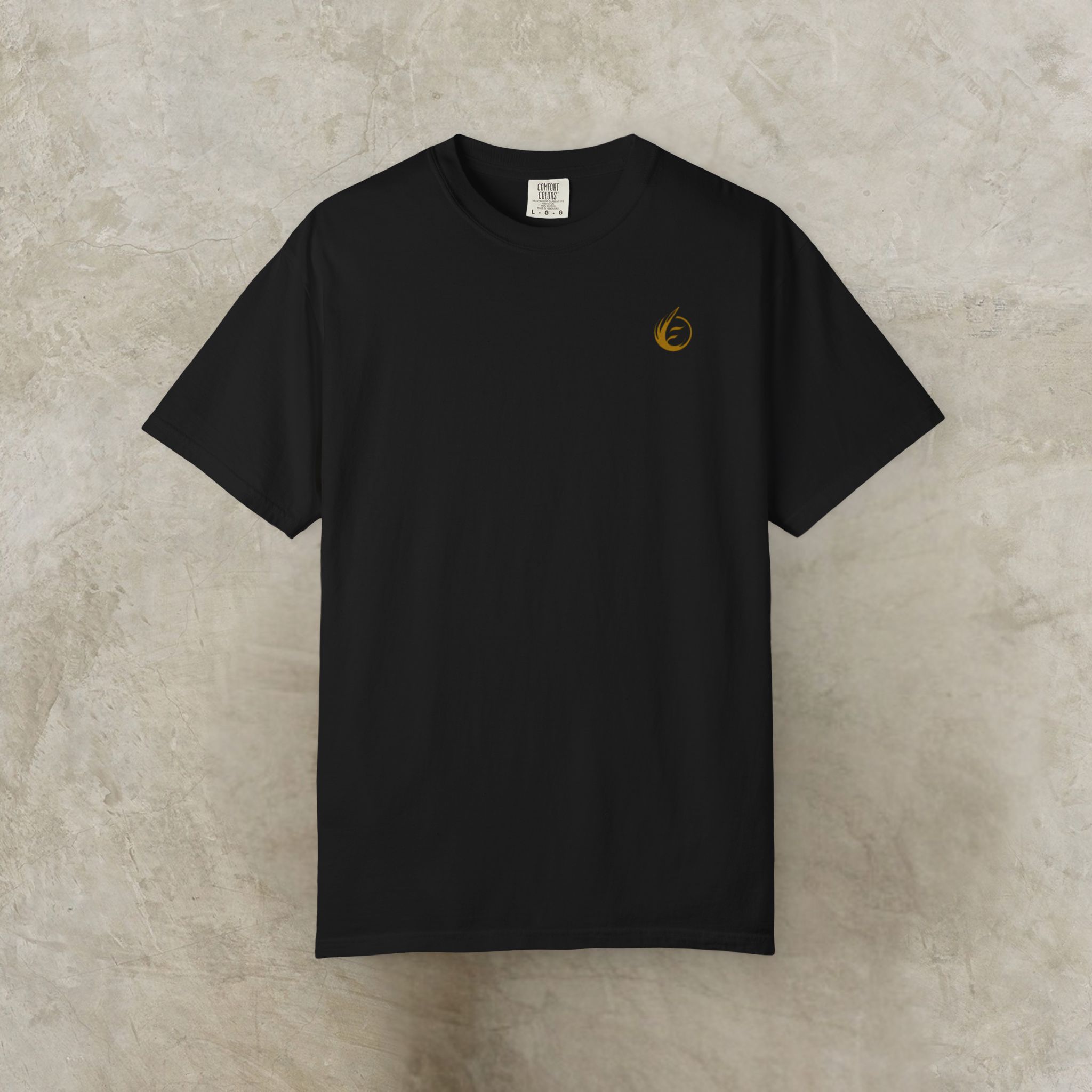 12394283997843036726_2048_customjpeg - Essence Innovation Black short-sleeve T-shirt laid flat on a textured concrete background with a small orange circular logo on the left chest area.