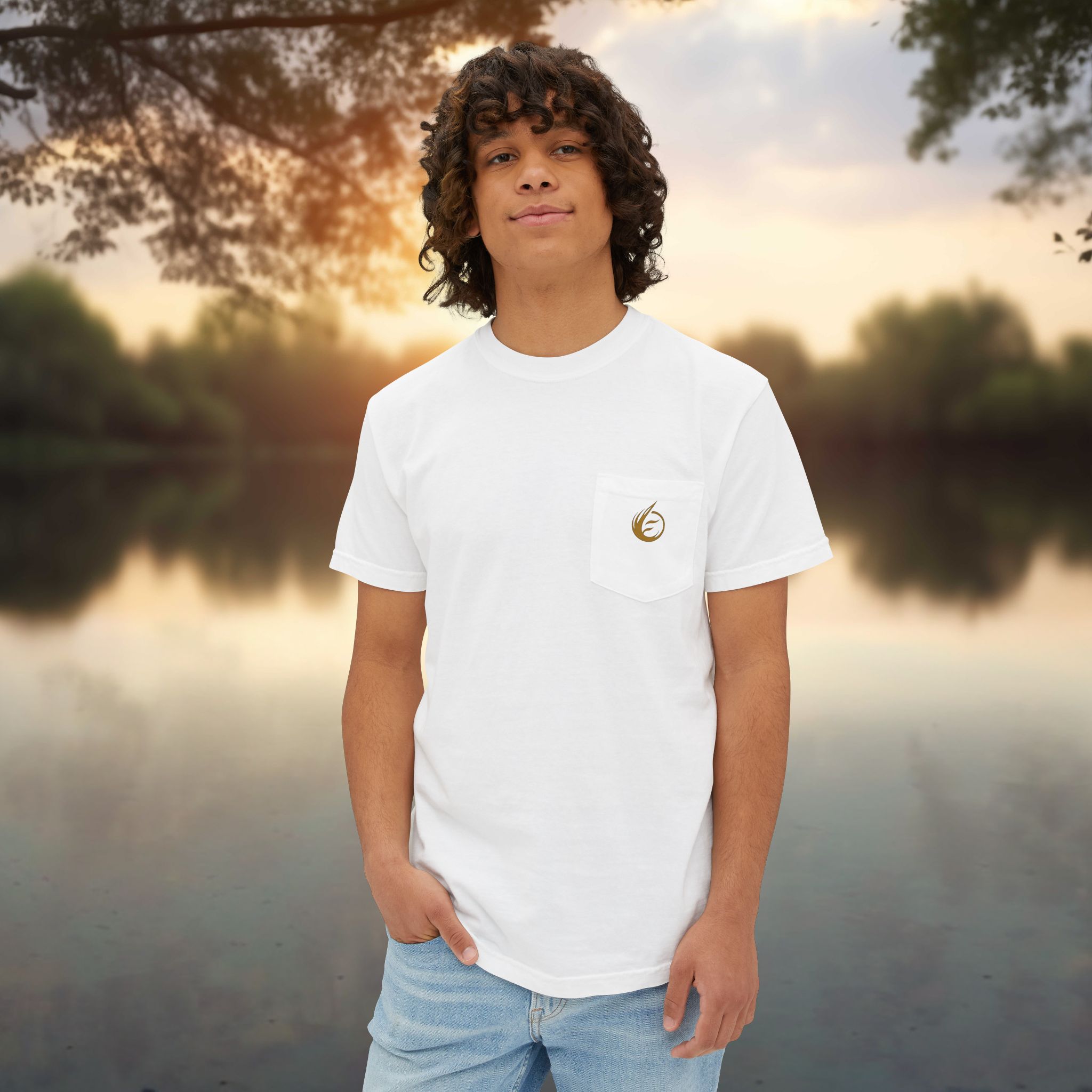 15118196139522335255_2048_customjpeg - Essence Innovation Person standing outdoors by a lake at sunset, wearing a white T-shirt and light blue jeans; warm evening light in the background.
