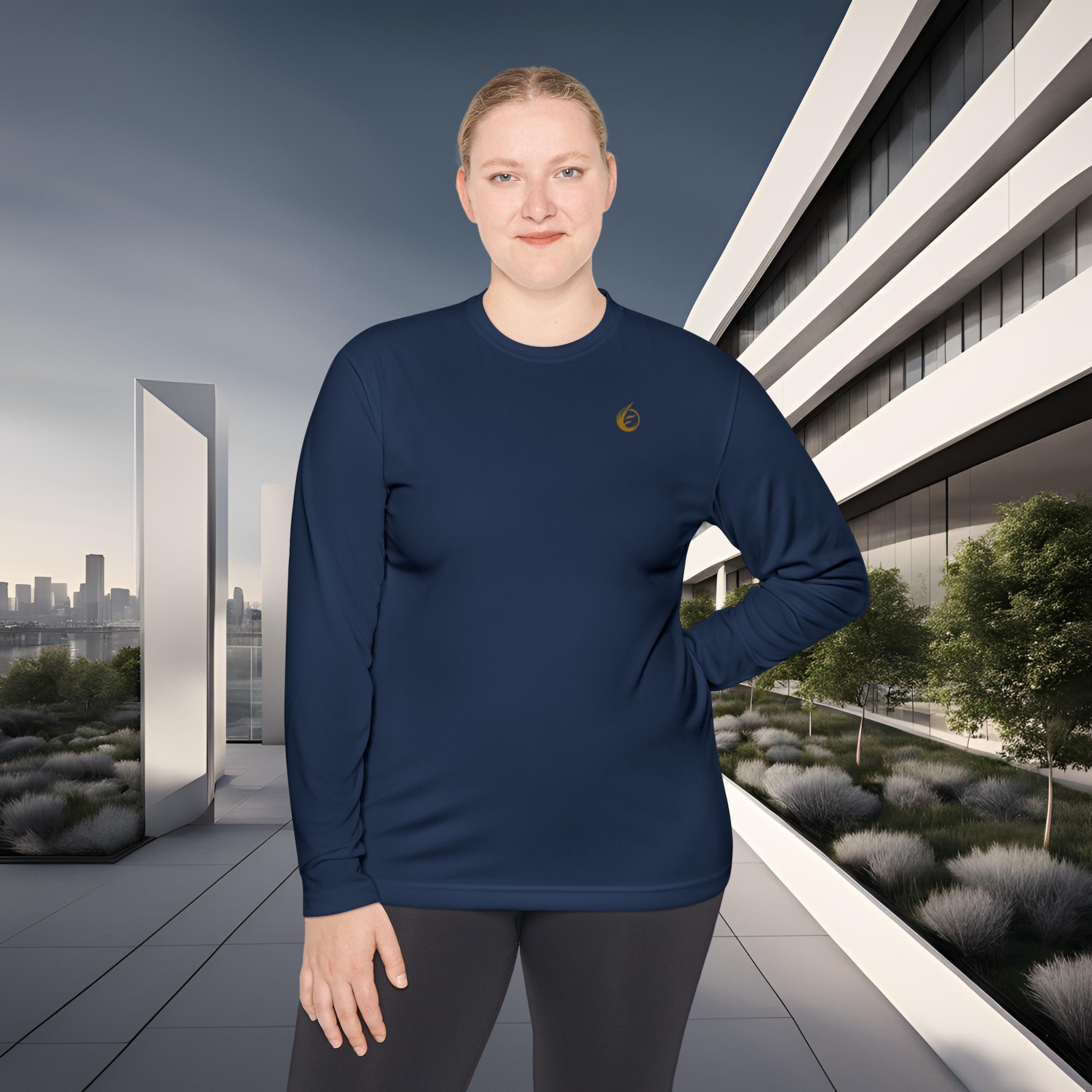 1532206187444555242_2048_customjpeg - Essence Innovation Person wearing a navy long-sleeve top with a small gold logo, standing outdoors in front of a modern white building and city skyline.
