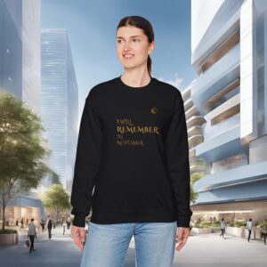 18114071046569211511_2048_customjpeg - Essence Innovation Portrait of a woman in a black sweatshirt with gold text, standing in a modern urban plaza against a blue sky backdrop, looking to the side.