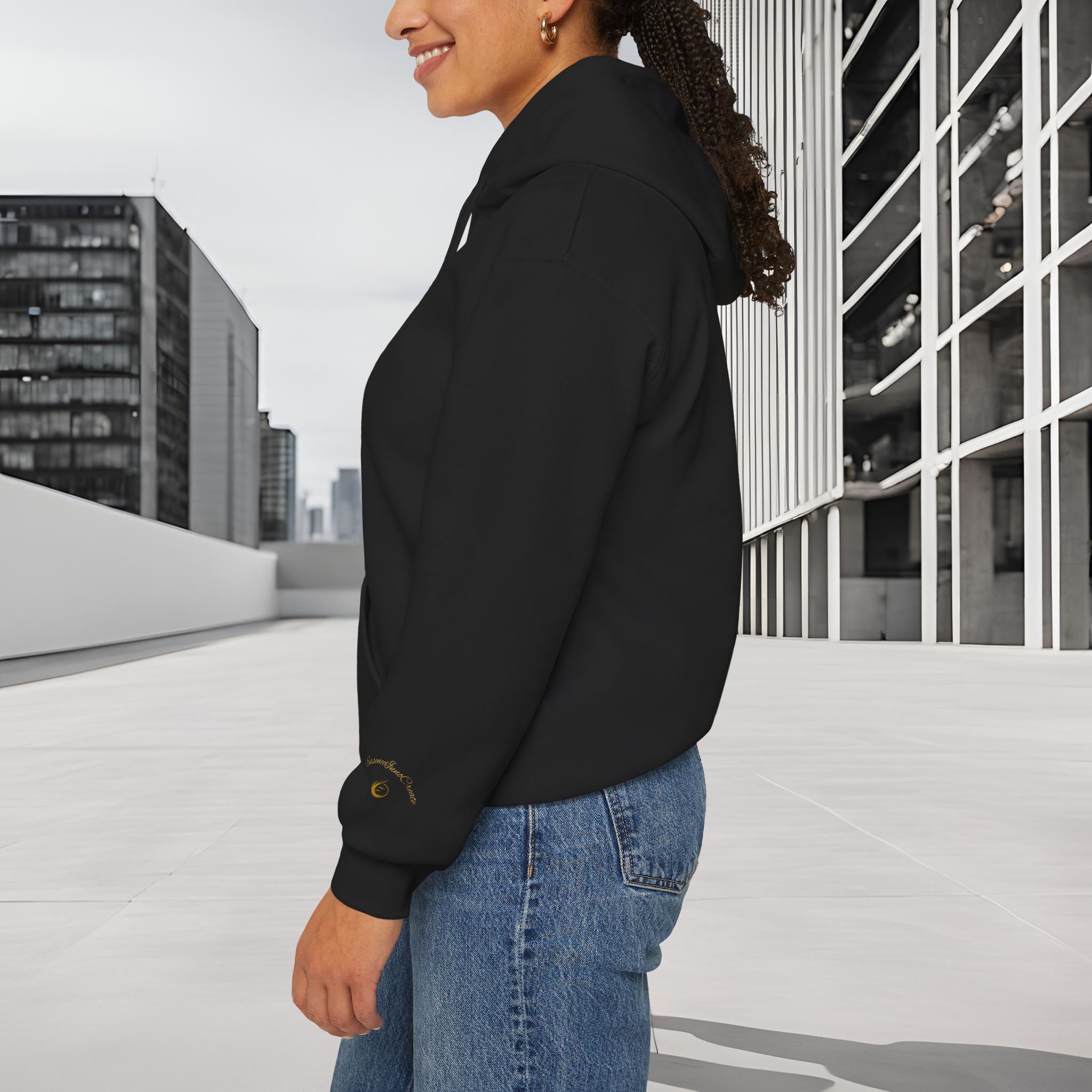 404980444562871495_2048_customjpeg - Essence Innovation Person shown from the side wearing a black hoodie and blue jeans on a rooftop or balcony, with modern glass buildings in the background.