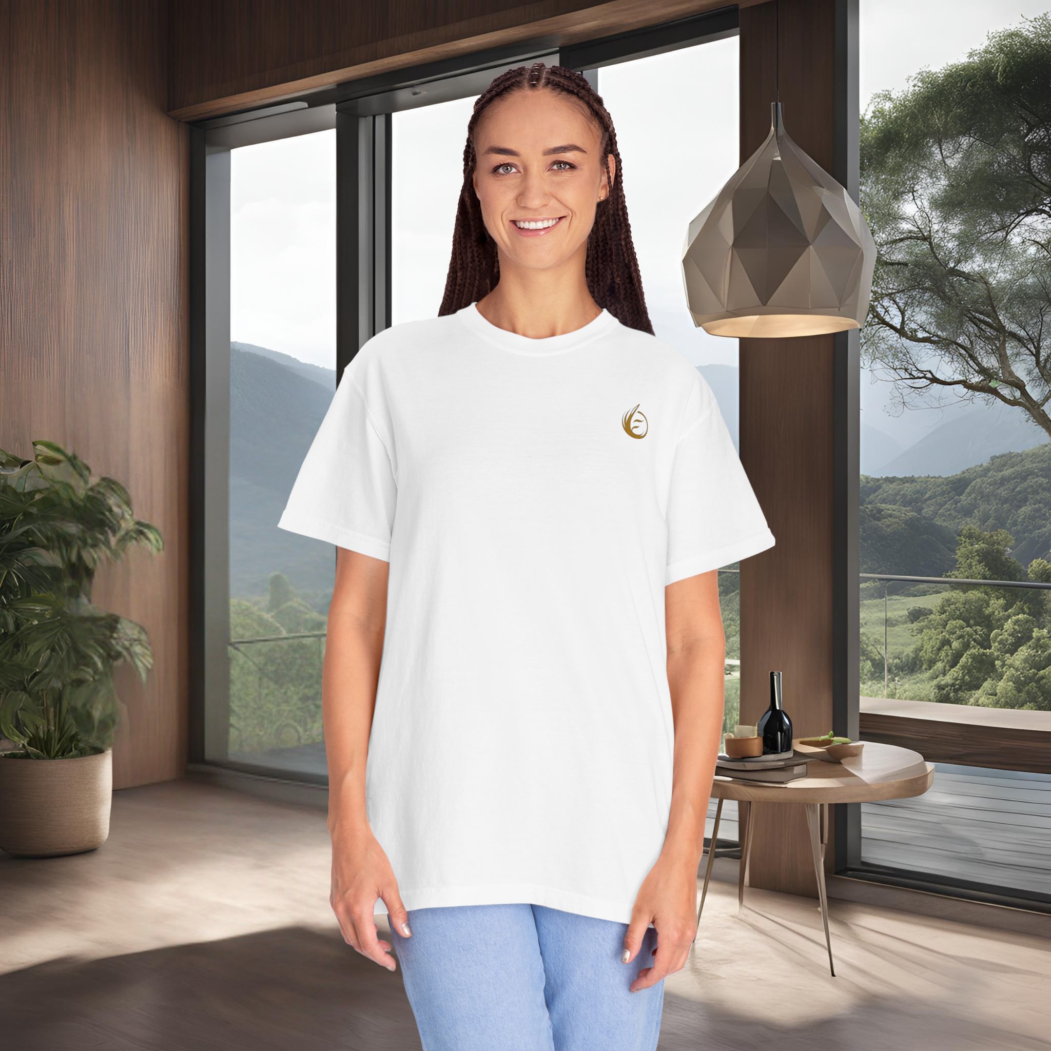 5234819625182733556_2048_customjpeg - Essence Innovation Smiling woman with braided hair in a white t-shirt stands indoors near a wooden wall and large windows, mountains visible outside.
