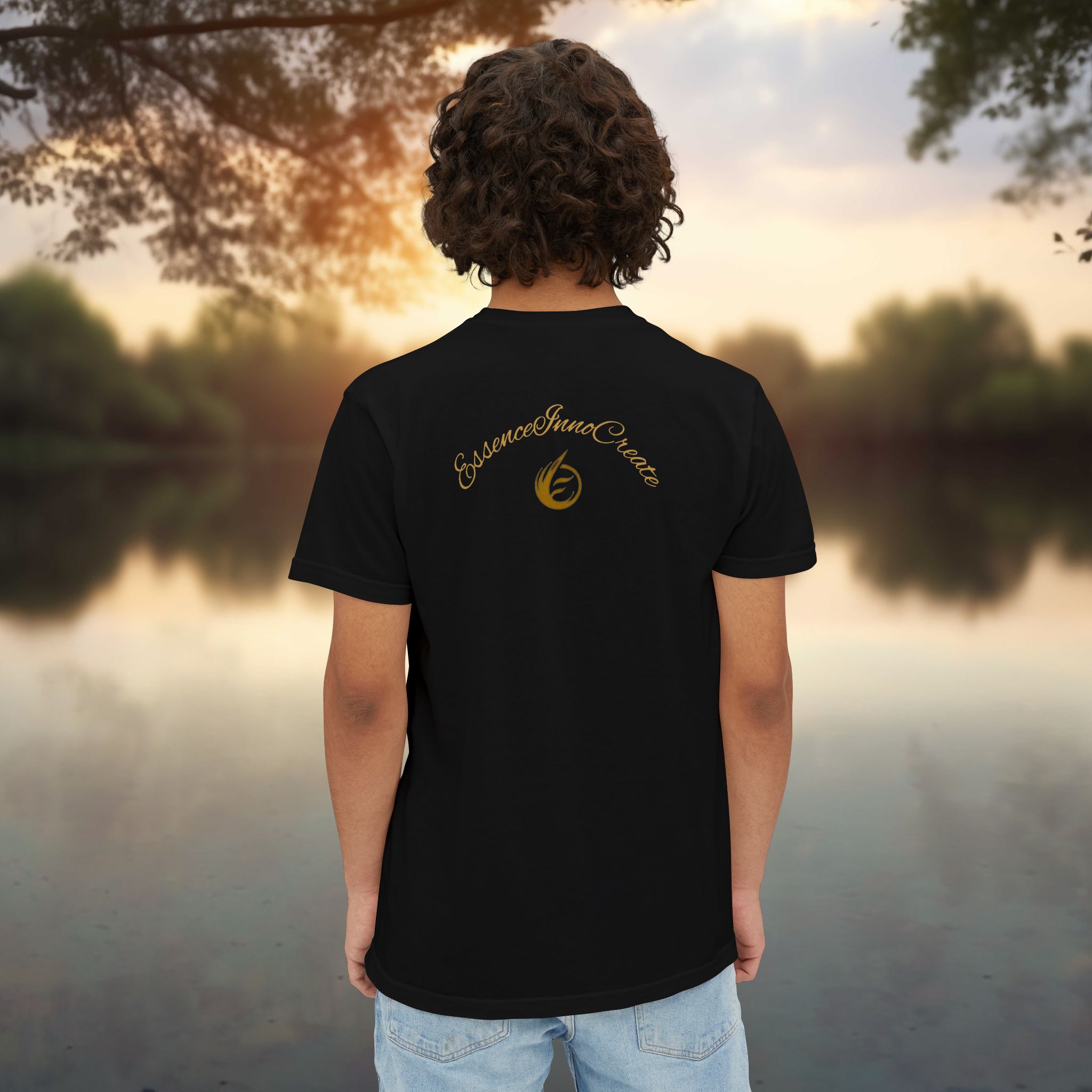 6163271186230898404_2048_customjpeg - Essence Innovation Person facing away from the camera, wearing a black T-shirt with a gold scripted logo on the back, outdoor sunset scene.