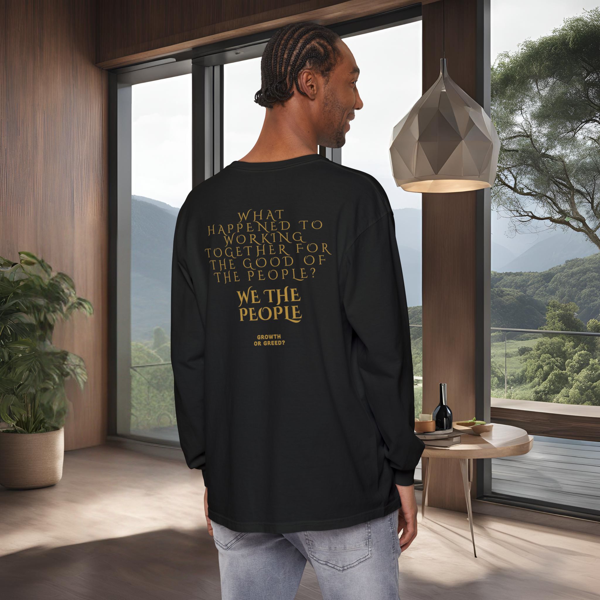 8225162413305107602_2048_customjpeg - Essence Innovation Back view of a man in a black shirt with gold text, standing inside a modern room by large windows overlooking mountains; a geometric pendant lamp hangs nearby.