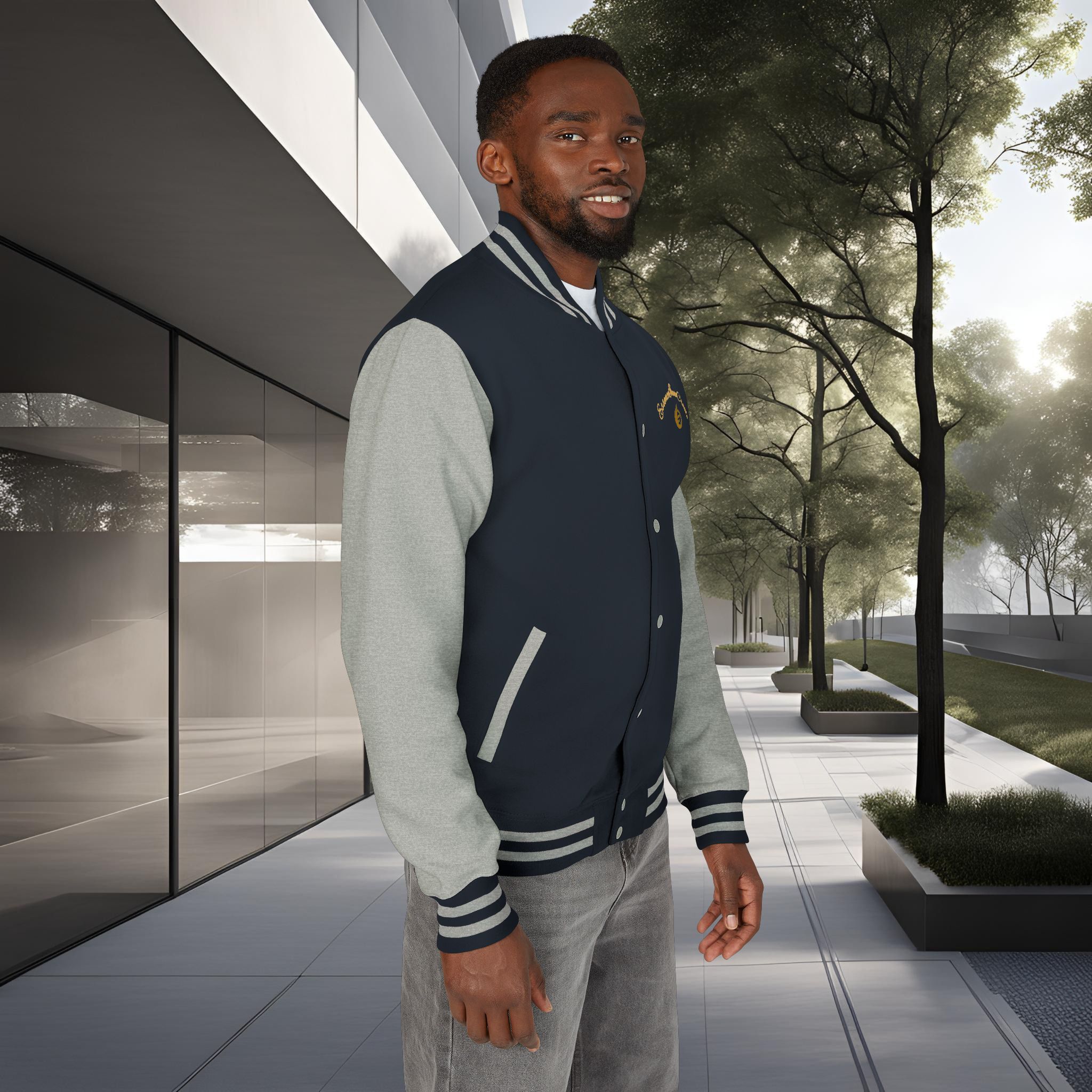 8263362966003343166_2048_customjpeg - Essence Innovation Man standing outdoors beside a modern glass building, wearing a navy varsity jacket with gray sleeves.
