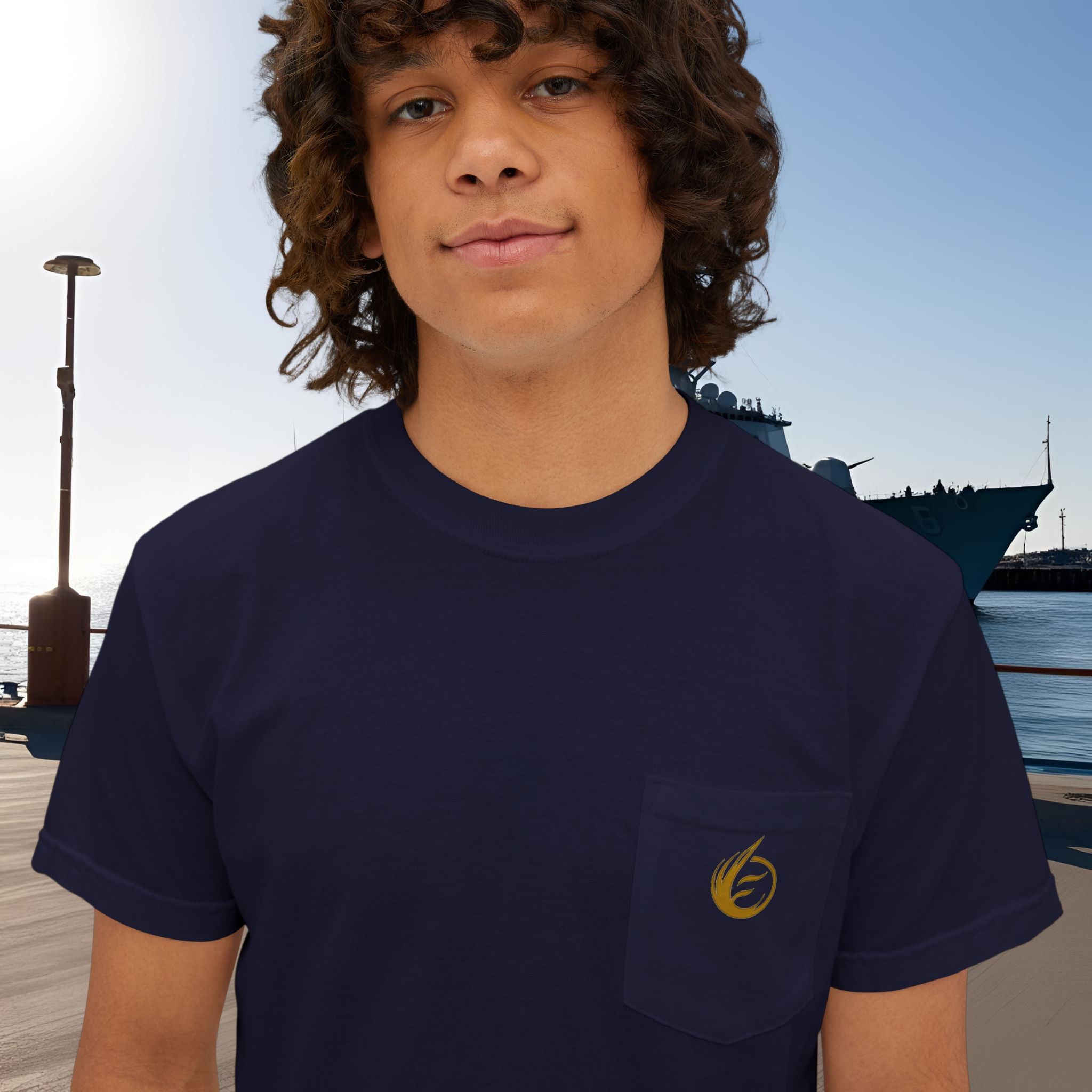 9357977553841057331_2048_customjpeg - Essence Innovation Close-up of person wearing a dark navy T-shirt with a gold emblem, outdoor port scene in the background